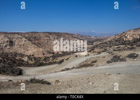 Pays poussiéreux sec avec peu de végétation sur les collines. Ciel bleu. Construction d'une nouvelle route au sud de la crête, la Grèce. Banque D'Images