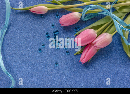 Tulipe rose avec ruban bleu sur bleu glitter background with copy space Banque D'Images