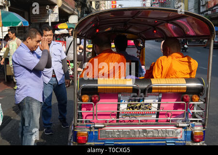 Un tuk-tuk driver dans Chinatown, Bangkok, Thaïlande, accueille respectueusement ou "WAIS" deux moines bouddhistes assis dans un tuk-tuk, un trois-roues mini-taxi Banque D'Images