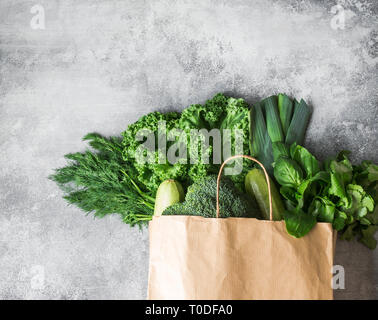 Ingrédients végétaliens vert sain pour la cuisson. Nettoyer les légumes verts et les herbes dans un sac de papier sur fond gris. Produits du marché sans Banque D'Images