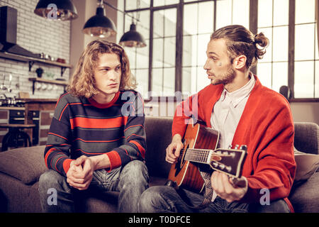 L'homme aux cheveux blonds et sérieux à l'écoute de sa musique tutor Banque D'Images