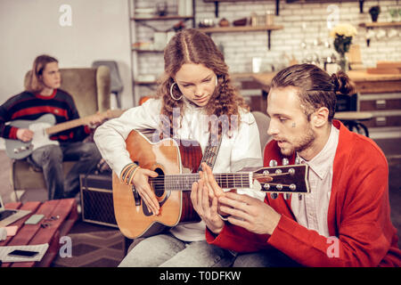 Tuteur l'enseignement aux adolescents à jouer de la guitare dans le salon Banque D'Images