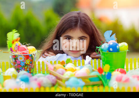 Portrait d'une jolie fille près de la table avec beaucoup des oeufs colorés, symbole traditionnel de Pâques, une grande fête chrétienne de printemps Banque D'Images