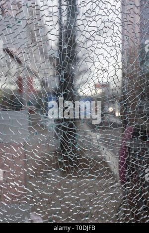 Close-up of a broken et verre brisé volet ou une fenêtre, vue sur la ville floues en arrière-plan. Banque D'Images