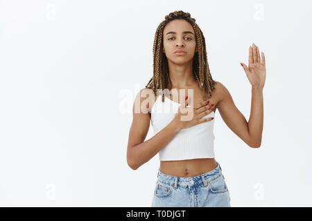 Je jure de dire la vérité. Portrait de fidèle et loyal-grave à la charmante femme à la peau sombre avec des dreads palm gauche et droite sur holding Banque D'Images
