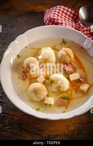 Bol de bouillon de printemps avec des boulettes de moelle osseuse, des légumes frais et des herbes vue grand angle sur une table rustique pour la publicité Banque D'Images