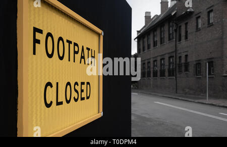 Jaune, le sentier fermé mise en garde sur une clôture noire à l'extérieur d'un site de construction Banque D'Images