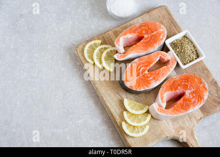 Poisson frais. darnes de saumon frais avec le citron, les épices et le sel sur une planche à découper Banque D'Images