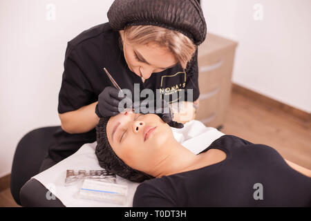 Cosmetologist femme faisant un sourcil méthode de dépose de tatouage sur une cliente. Traitement de la peau. La technologie moderne. Salon de beauté. Banque D'Images