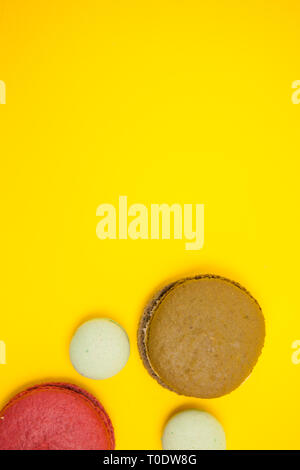 Vue du dessus de l'autre des macarons de couleur sur fond jaune. Dessert français Banque D'Images