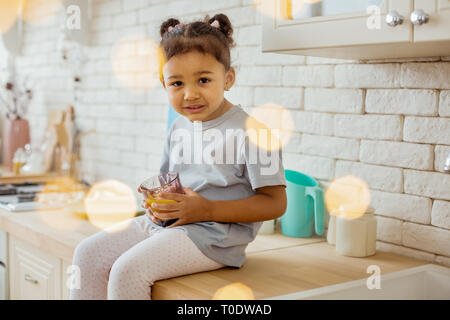 Une femme aux cheveux bouclés peu holding glass avec le jus Banque D'Images