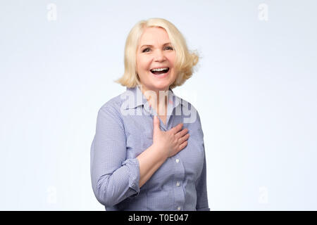 Woman with Blonde hair in blue shirt smiling posant au studio. Banque D'Images