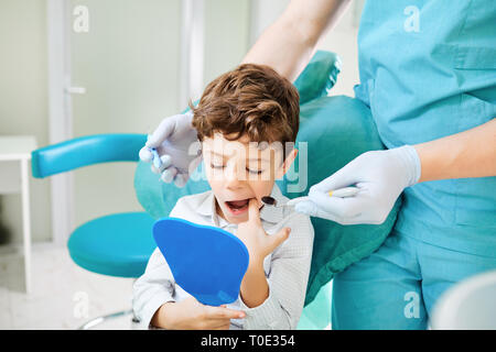 Dentiste et enfant garçon regarde dans le miroir au niveau des dents Banque D'Images