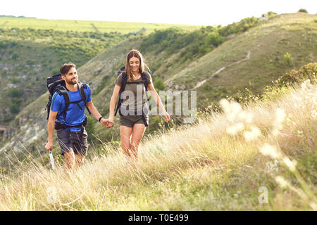 Un couple de voyageurs avec des sacs à dos, rendez-vous sur une route. Banque D'Images