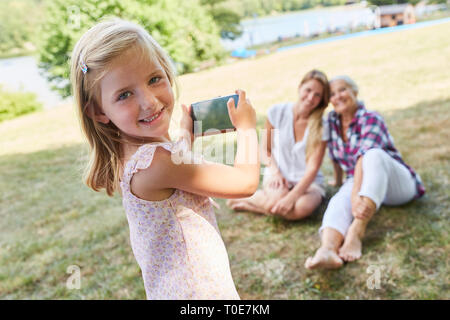 Petite fille est photographié avec le smartphone de sa mère et de sa grand-mère Banque D'Images