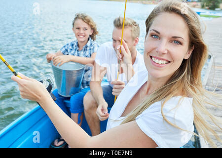 Femme joyeuse à la pêche avec l'ensemble de la famille dans le bateau sur un lac Banque D'Images