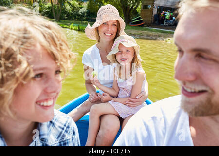 Famille avec deux enfants en barque sur un lac en vacances d'été Banque D'Images