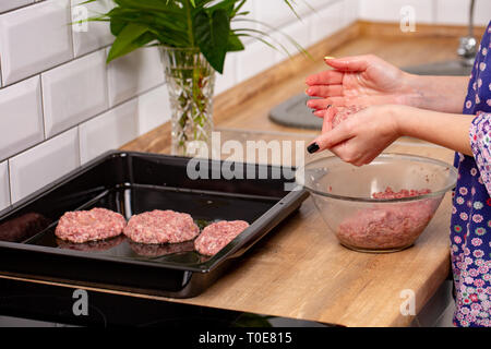 La viande hachée crue dans les mains de femme svelte. La cuisine de fille sur escalopes cuisine moderne Banque D'Images