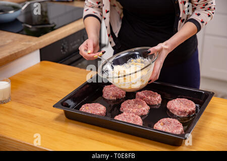 Fonds de main de femme theminced ou boulettes de viande de la farce portant sur un processus de cuisson. noir de la cuisine maison. Banque D'Images