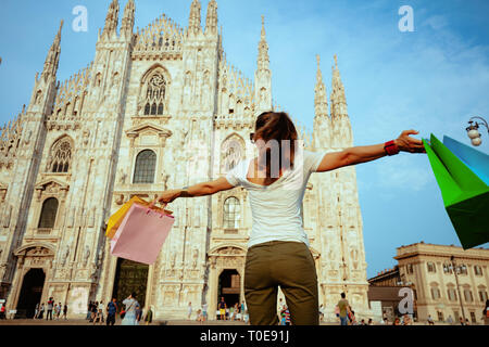 Vus de derrière, solo élégant femme touristiques en blanc T-shirt et lunettes de réjouissance la marche avec des sacs colorés dans l'avant de la cathédrale en Banque D'Images