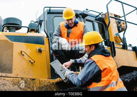 Travailleur avec de lourdes machines d'excavation à l'exploitation minière Exploitation Banque D'Images