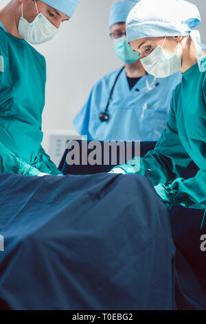 Les médecins et chirurgiens opérant patient in hospital Banque D'Images