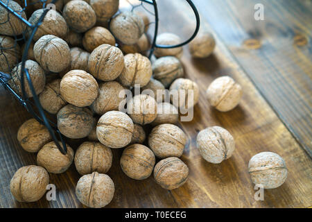 Noix biologiques crus dans le shell sur le vieux fond de bois marron en style rustique. Les écrous de la récolte d'un pays. Des ingrédients sains dans le cadre de la diététique. Close up. Banque D'Images