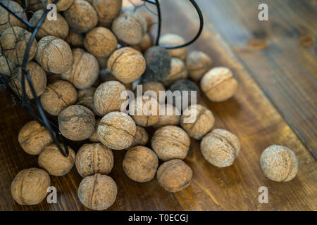 Noix biologiques crus dans le shell sur le vieux fond de bois marron en style rustique. Les écrous de la récolte d'un pays. Des ingrédients sains dans le cadre de la diététique. Close up. Banque D'Images