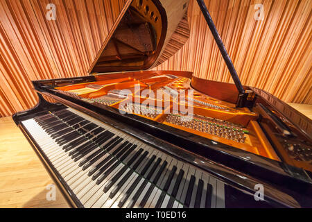 Un grand piano avec couvercle soulevé révélant l'intérieur du piano.