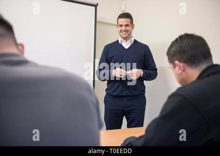 Un homme blanc dans un cavalier bleu est titulaire d'une présentation de formation pour d'autres collègues de travail dans un bureau, salle de réunion Banque D'Images