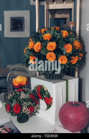 Un énorme bouquet de belles roses orange décoré dans l'intérieur, sur fond blanc, table de chevet. Banque D'Images