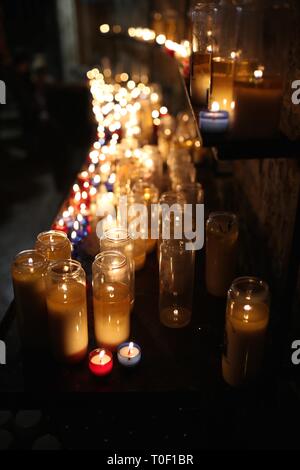 Une belle rangée de bougies votives blanches clignotantes s'allument une église sombre Banque D'Images