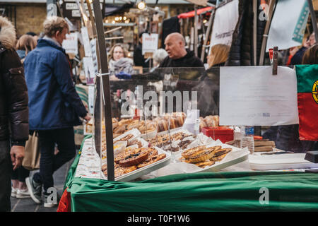 Londres, Royaume-Uni - 16 mars. 2019 : l'achat de gâteaux et tartes faits à partir d'un stand au marché de Greenwich, London's seul marché situé dans un site du patrimoine mondial. Banque D'Images