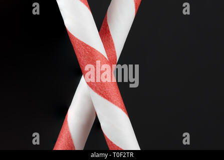 Macro portrait Présentation de deux pailles papier rouge et blanc sur fond noir Banque D'Images