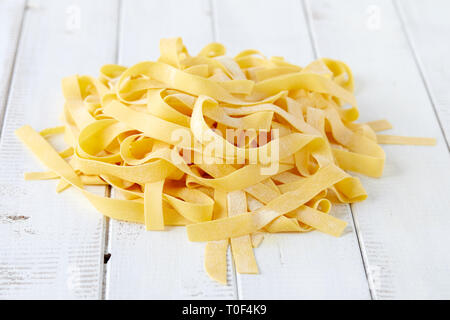 Des pâtes pappardelle brut blanc sur fond de bois. Banque D'Images