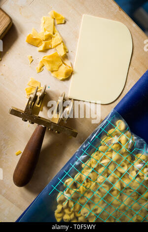 Coupe-pâte, une roue marysa spatule en plastique pour couper la pâte et un sac en plastique avec tortellini prêt faites , sur un fond de bois Banque D'Images