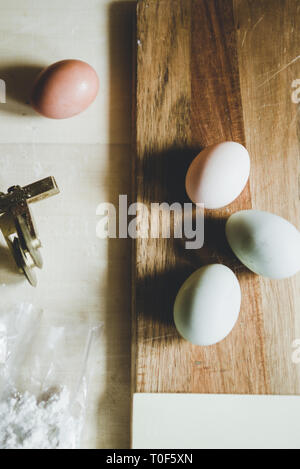 Faire des pâtes à la maison, les oeufs vert olive, Egger, oeuf blanc et brun, la farine et les pâtes cutter sur un fond de bois Banque D'Images