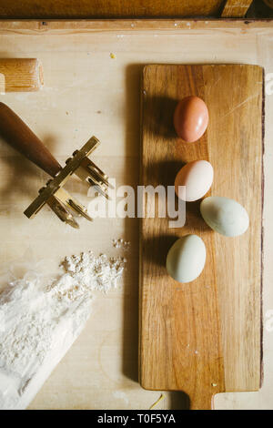 Faire des pâtes à la maison, les oeufs vert olive, Egger, oeuf blanc et brun, la farine et les pâtes cutter sur un fond de bois Banque D'Images