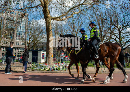 Les agents de police néerlandais sont vus en passant par avec les chevaux autour du site commémoratif. Le jour après trois personnes ont été tués et cinq blessés lors d'un tournage sur un tramway dans la ville néerlandaise d'Utrecht, des centaines de personnes ont été de placer des fleurs et des lettres de consolation pendant toute la journée, à l'Oktoberplein l'endroit où l'arrêt de tram et un homme a commencé à tirer. Banque D'Images
