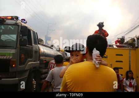 Quezon City, Philippines. Mar 20, 2019. Un garçon couvre son nez durant un incendie dans un bidonville à Quezon City, Philippines, le 20 mars 2019. Plus de 250 chantiers ont été rasées dans le feu, laissant 750 familles sans abri. Credit : Rouelle Umali/Xinhua/Alamy Live News Banque D'Images