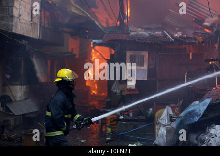 Quezon City, Philippines. Mar 20, 2019. Un pompier essaie d'éteindre un incendie dans un bidonville à Quezon City, Philippines, le 20 mars 2019. Plus de 250 chantiers ont été rasées dans le feu, laissant 750 familles sans abri. Credit : Rouelle Umali/Xinhua/Alamy Live News Banque D'Images