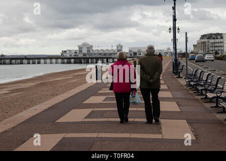 Un couple en train de marcher le long de la promenade de la plage de Southsea sur un jour froid et venteux mars Banque D'Images