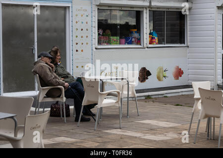 Couple de personnes âgées assis à l'extérieur d'un café en bord de boire une boisson chaude Banque D'Images