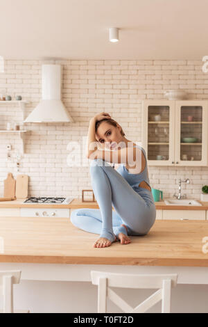 Jeune femme séduisante en costume bleu clair assis dans la posture tragique Banque D'Images