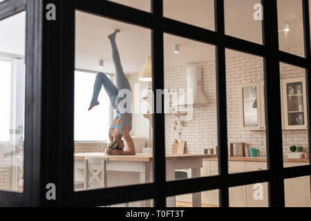 Athletic Girl ludique debout sur sa tête dans la cuisine Banque D'Images