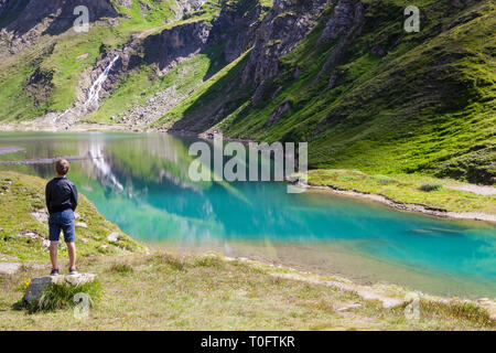 Un garçon regardant le lac appelé Speicher Nassfeld dans le Parc National du Hohe Tauern en Autriche Banque D'Images