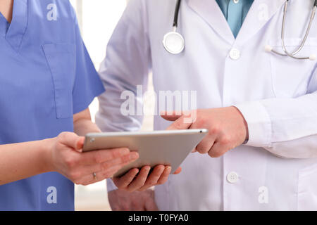 Doctor and nurse discussing patients essais a tablet computer in hospital Banque D'Images