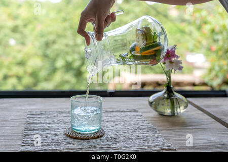 Serveur dans un restaurant de fruits de l'eau verse une carafe dans un verre, Close up Banque D'Images