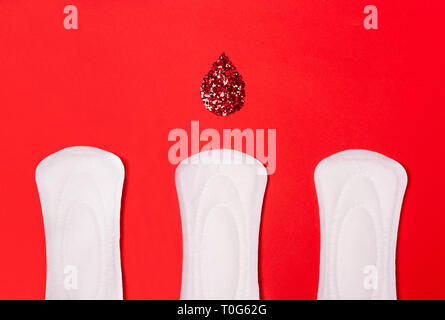 Trois serviettes sanitaires sur un fond rouge. La notion de jours critiques, la menstruation, les femmes cycle périodique. Banque D'Images