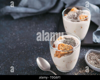 Pas de dessert gâteau au fromage cuit au four avec des biscuits écrasés les carottes et chia graines dans un bocal en verre sur fond sombre. Idées et recettes pour petit-déjeuner sain. L'espace de copie pour le texte. Banque D'Images